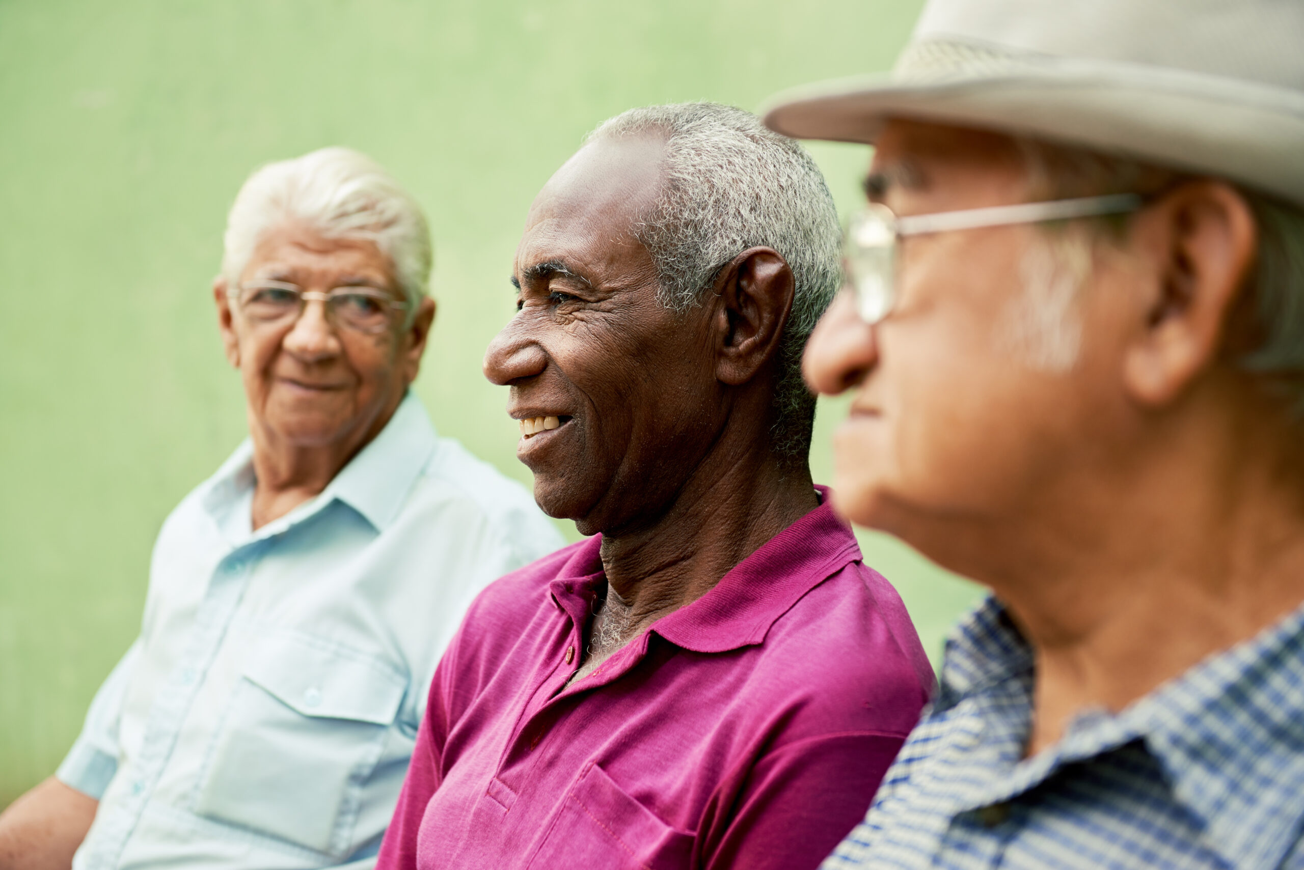 18064667_l retired elderly people and free time, group of happy senior african american and caucasian male friends talking and sitting on bench in park